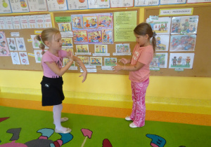 dwie dziewczynki w sali rozciągają gumkę w grze między swoimi palcami dłoni